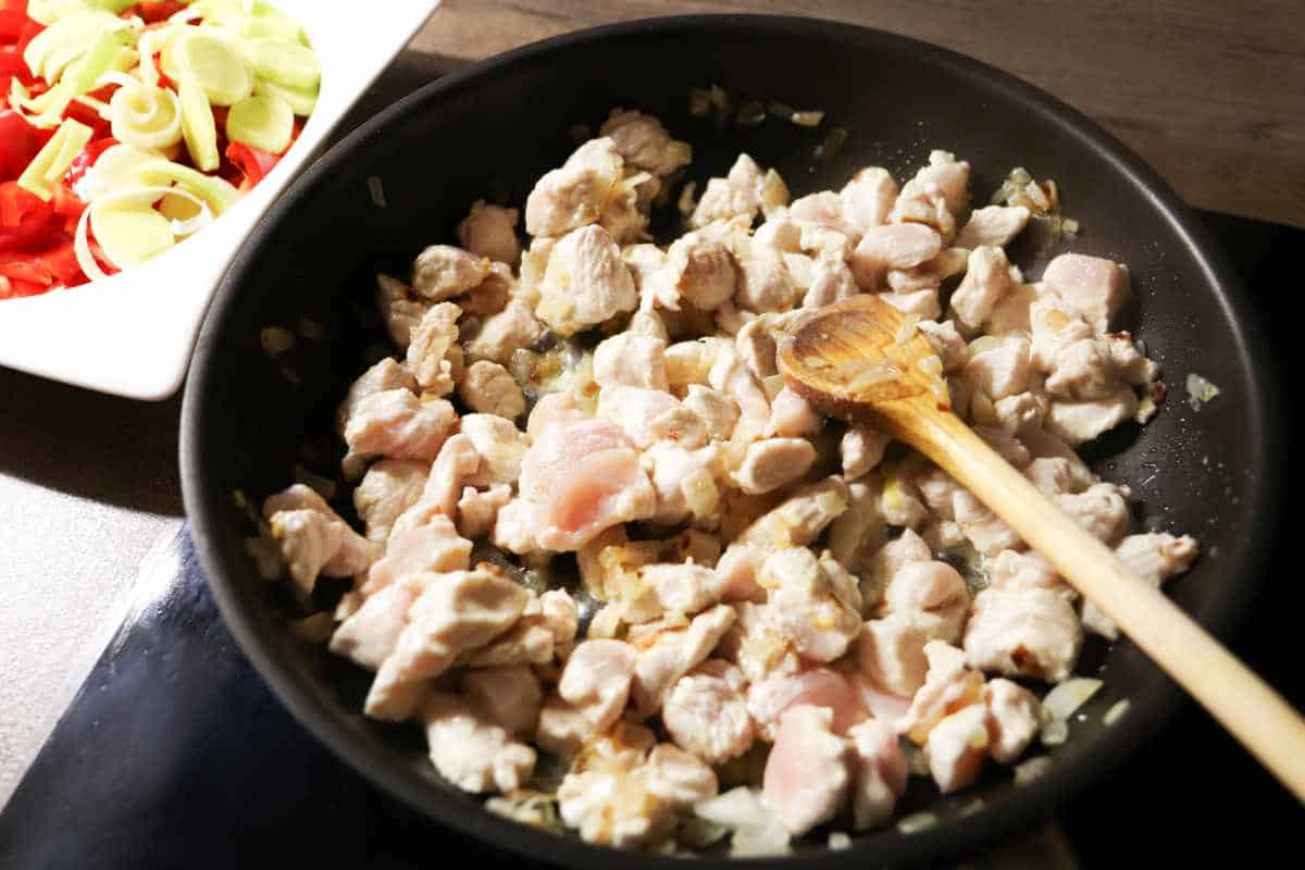 chicken cubes getting sauteed in a skillet.