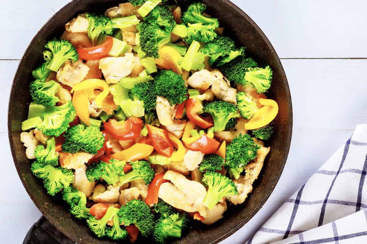 Vegetable dish stir fry with chicken in pan.