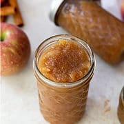 Ball canning jar filled with unsweetened applesauce, with sealed home canning jars in background.