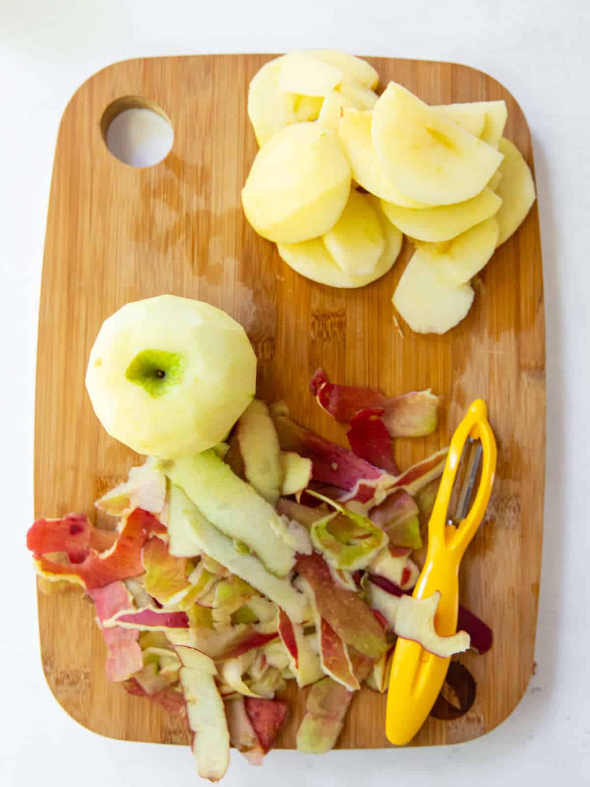 peeled, cored, and chunked apples on a wooden cutting board.