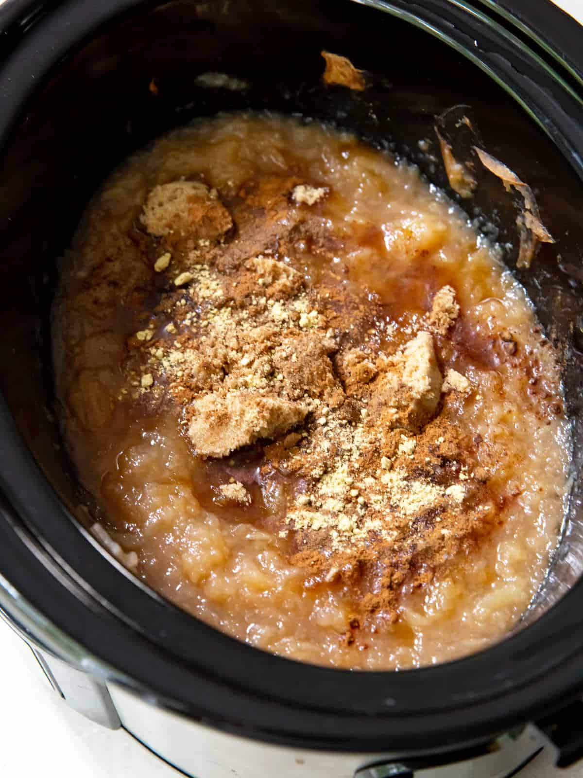 spices added to unsweetened applesauce in a crockpot.
