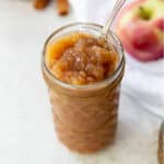Ball canning jar filled with homemade unsweetened applesauce, with a spoon.