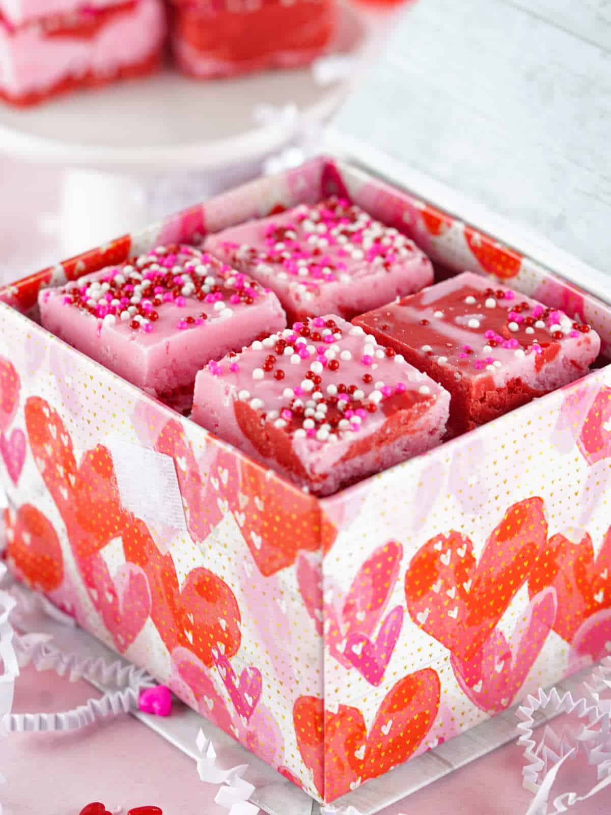 squares of pink and red strawberry fudge placed in a Valentine gift box.