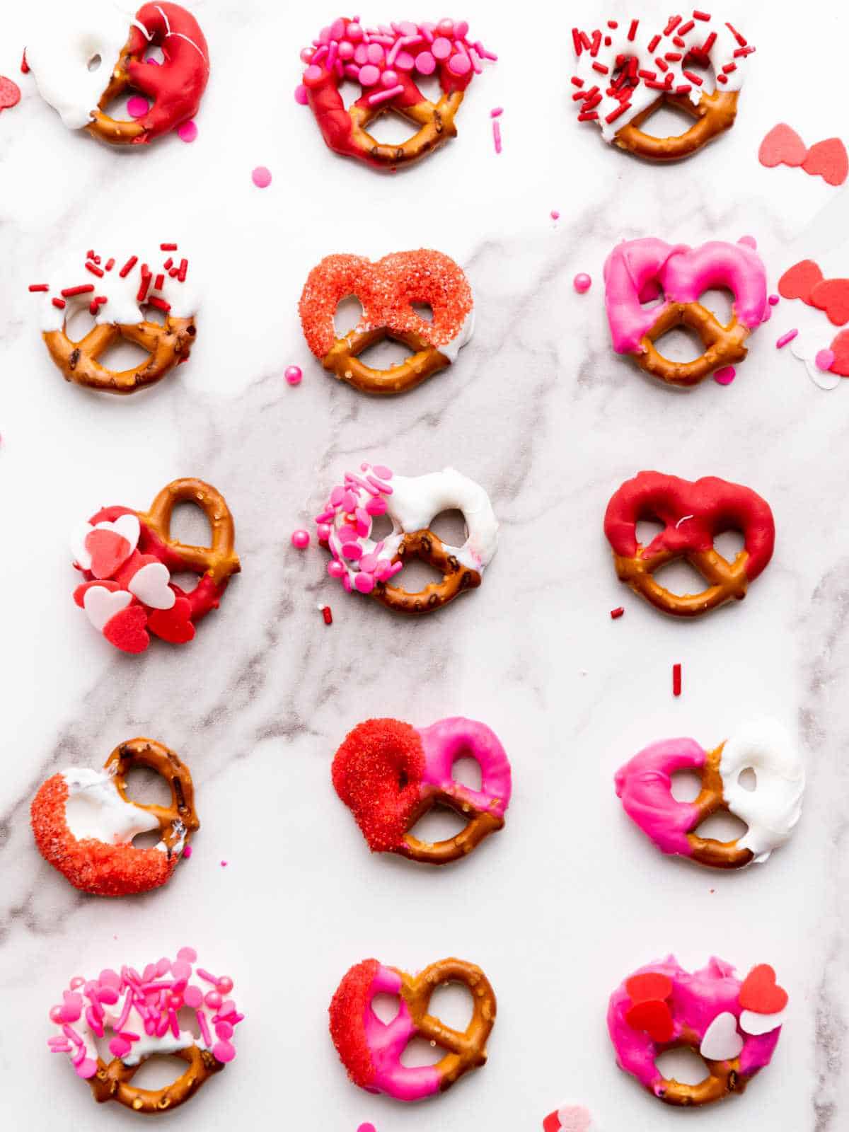 display of chocolate covered pretzels valentines dipped in red, pink, and white melted candy wafers with hearts and sugar decor. 