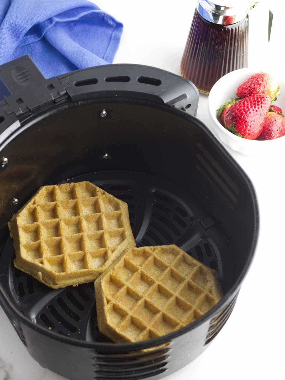 frozen waffles inside a air fryer basket.