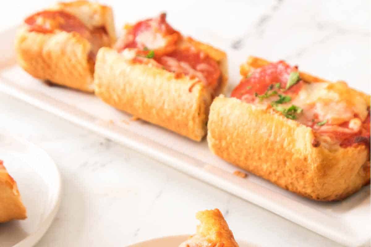 garlic bread with pepperoni on it on a plate with marinara sauce nearby.