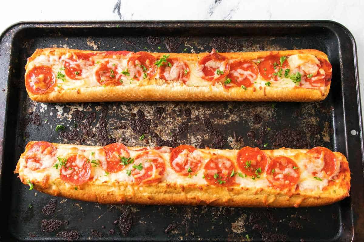 baking tray with topped bread and pizza toppings.