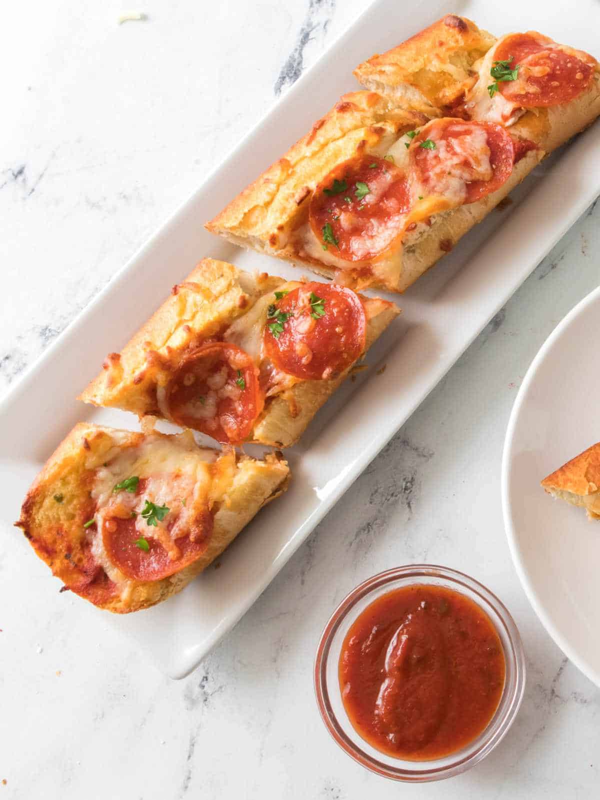 air fried pepperoni pizza on a plate with marinara sauce nearby.
