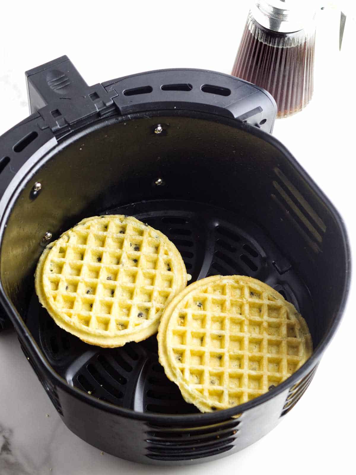 air fryer basket with two frozen waffles.