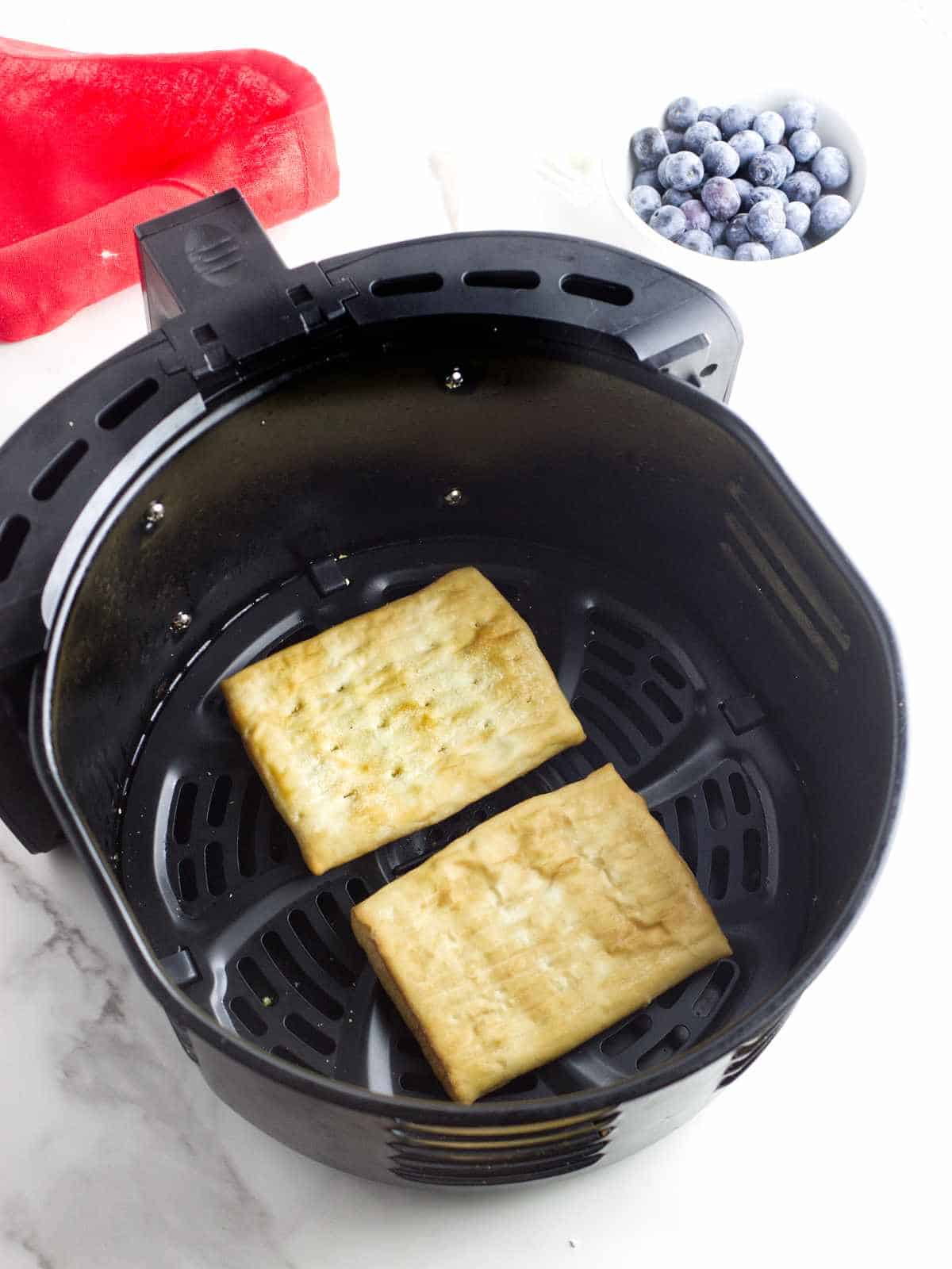 two rectangular pastries in an air frying basket.