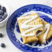 blue and white plate with iced golden brown pastries, and some blueberries on the white background.