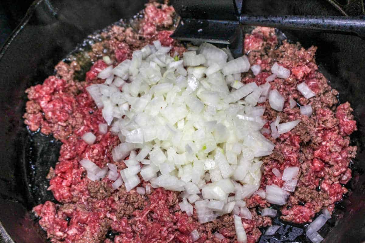 skillet with ground beef and diced onion cooking.