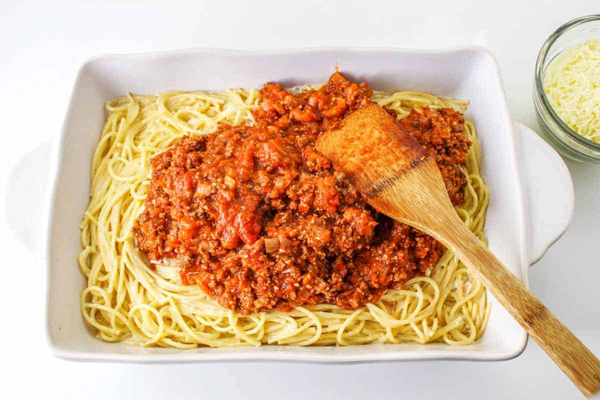 meat sauce poured on top of cooked Alfredo sauce and cooked spaghetti noodles.