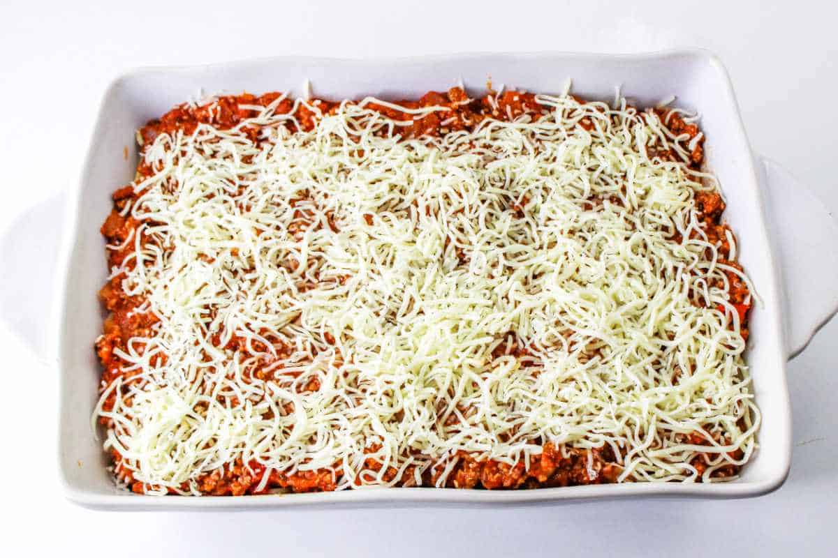 Casserole dish of pasta covered with shredded mozzarella cheese.