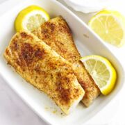 serving dish with blackened mahi mahi and lemon wedges with tartar sauce in a bowl.