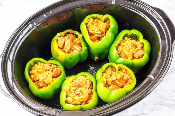 bell peppers stuffed with rice and sausae filling and placed in a crockpot.