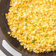 Cajun corn with parsley garnish in a cast iron skillet.
