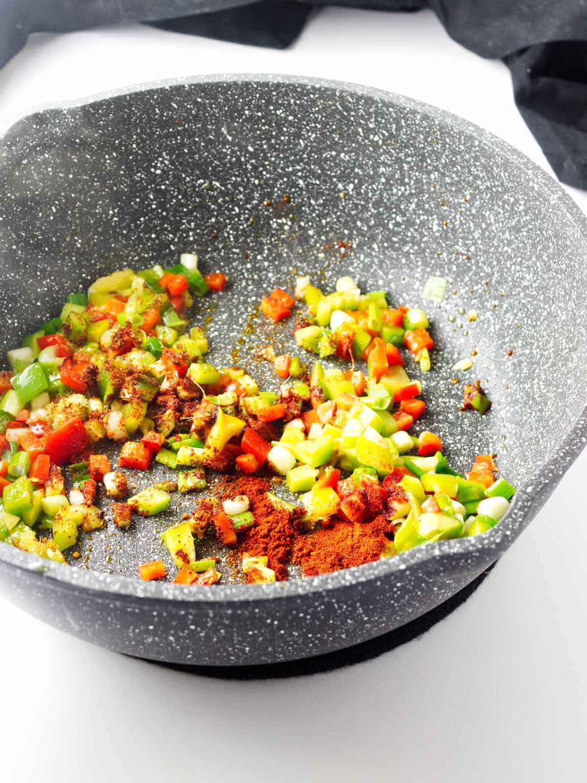 seasonings in a skillet of red and green bell peppers.