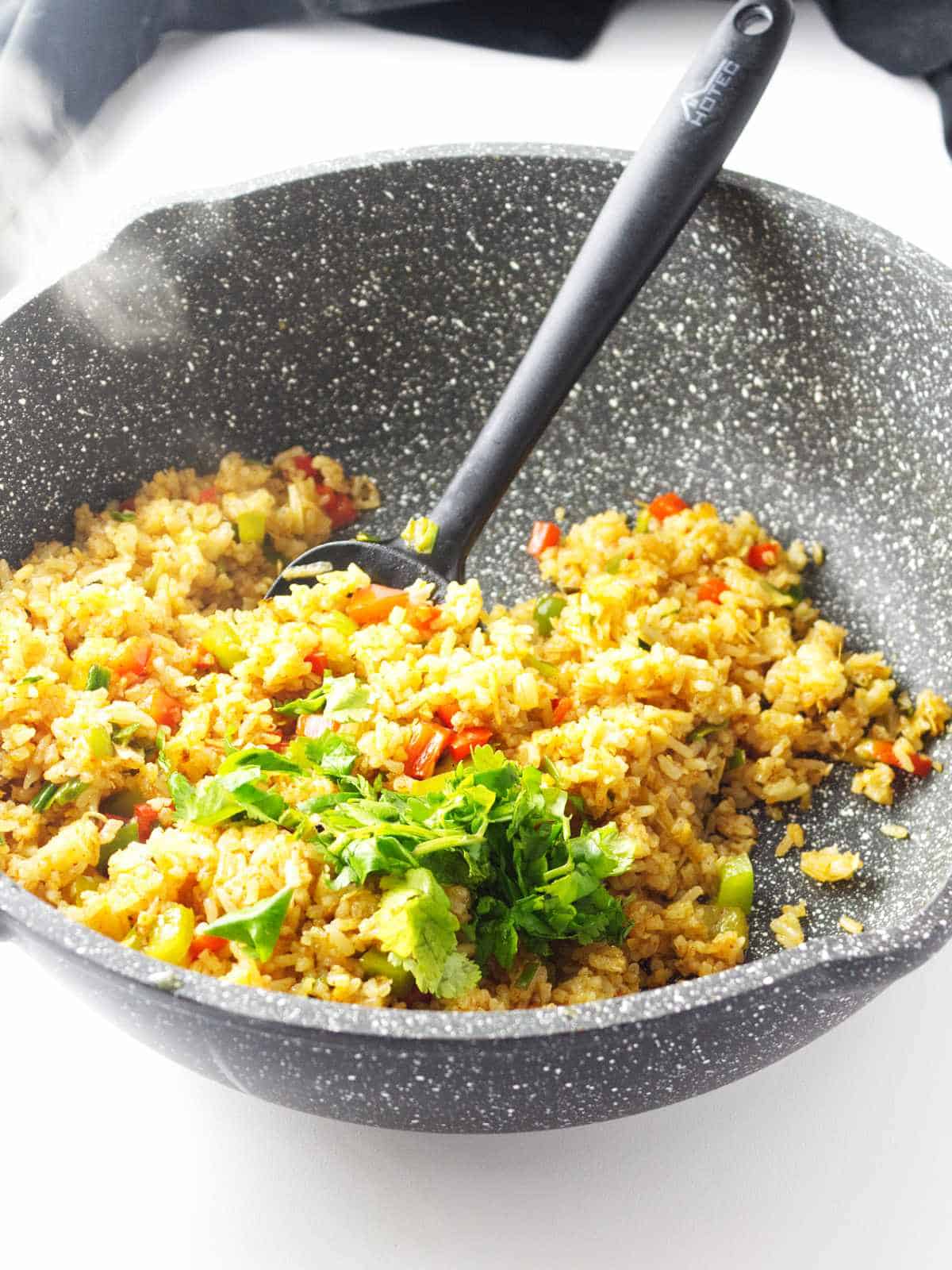 sauteed rice in a skillet with seasoning and vegetables.