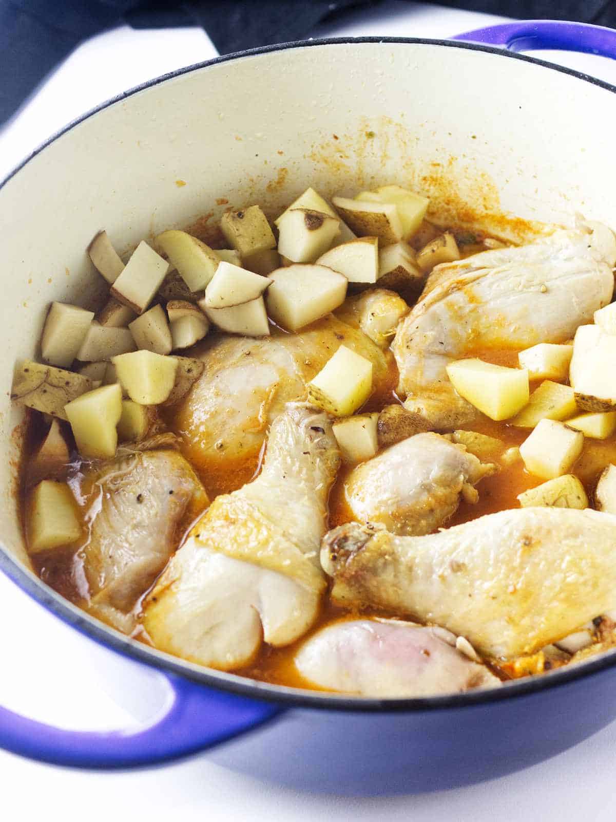 Adding chicken to Dutch oven with soup broth and vegetables.