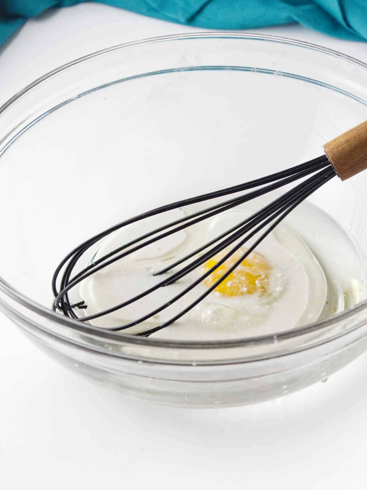oil and egg in a bowl with a whisk.