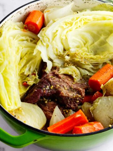 Dutch oven filled with cooked corned beef and cabbage.
