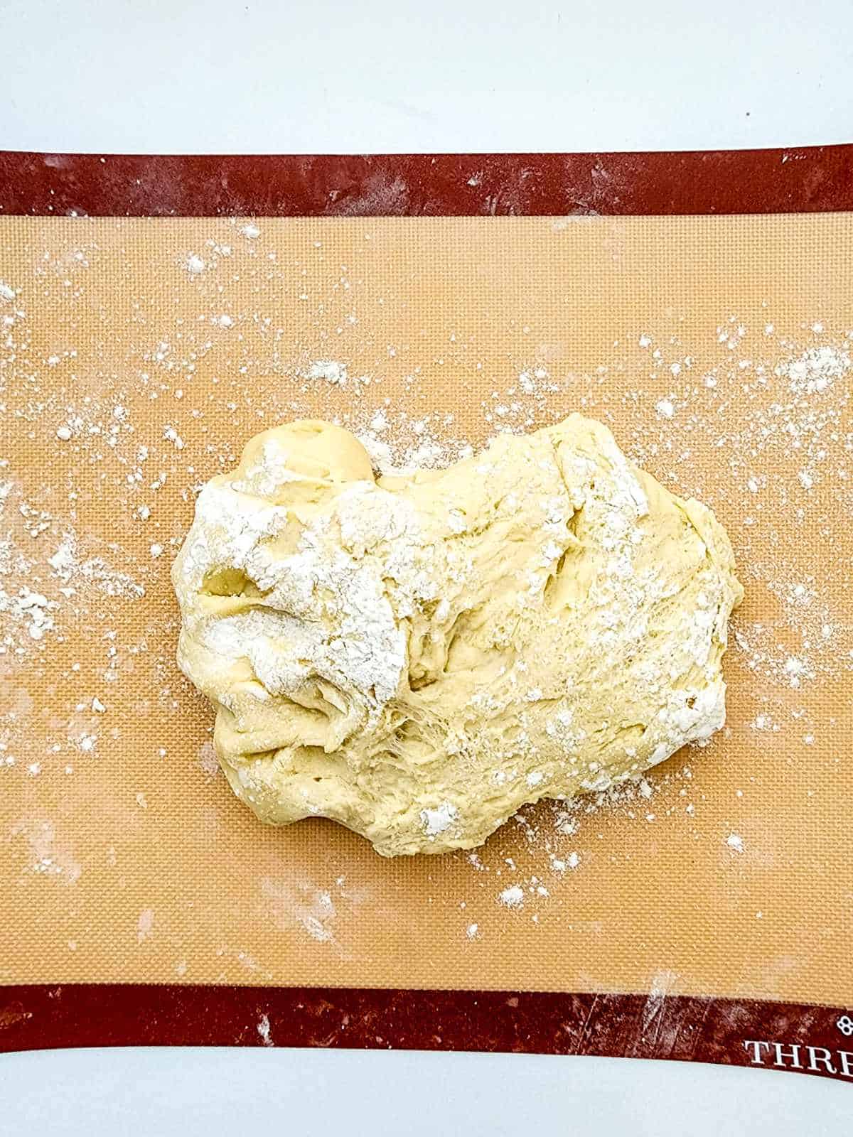 Ball of sweet dough on a rolling mat with a little flour to knead and shape dough.