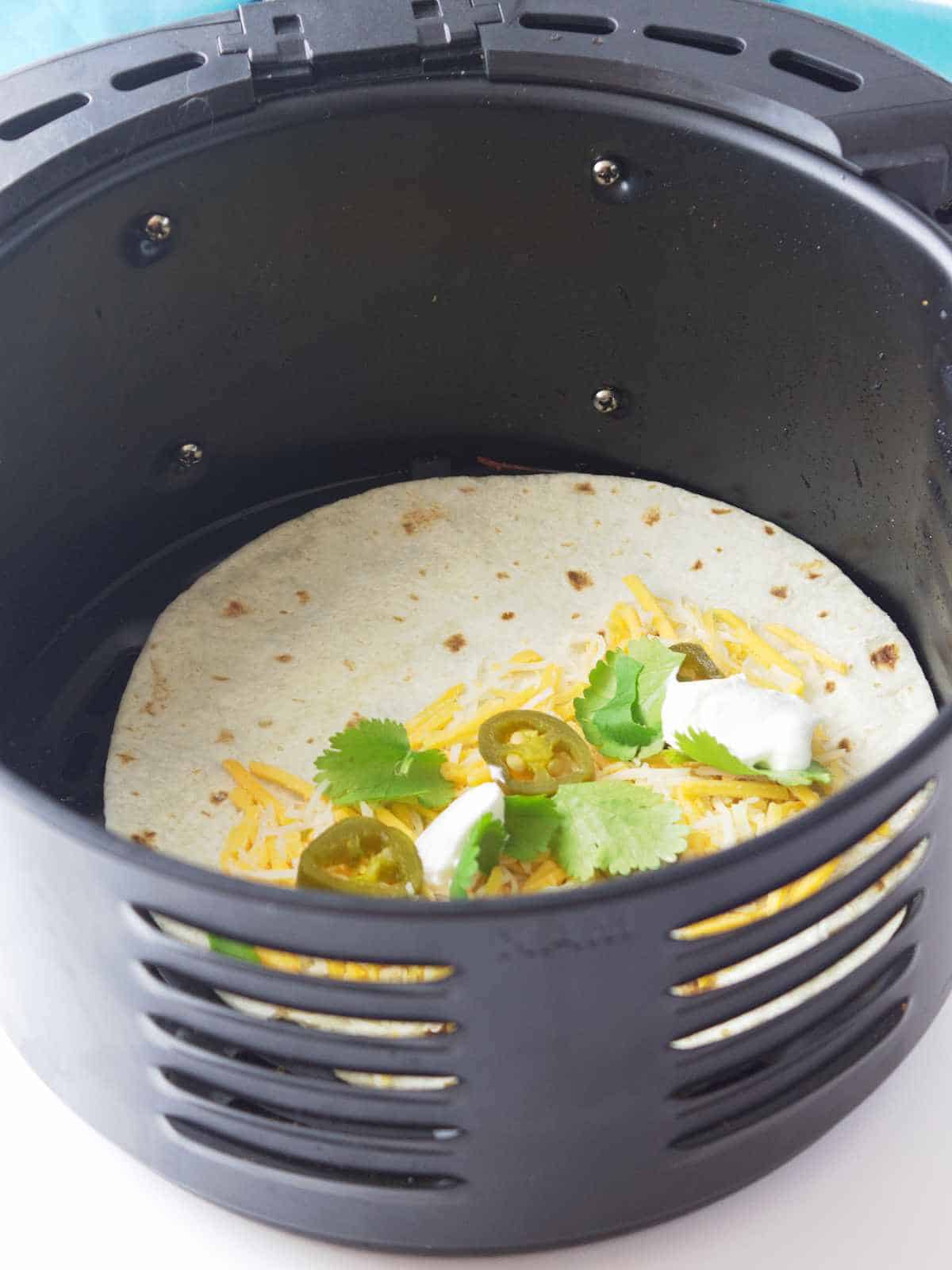 cheese quesadilla in an air fryer basket.