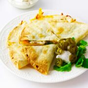 air fried quesadilla cut into thirds with cilantro and sour cream garnish.