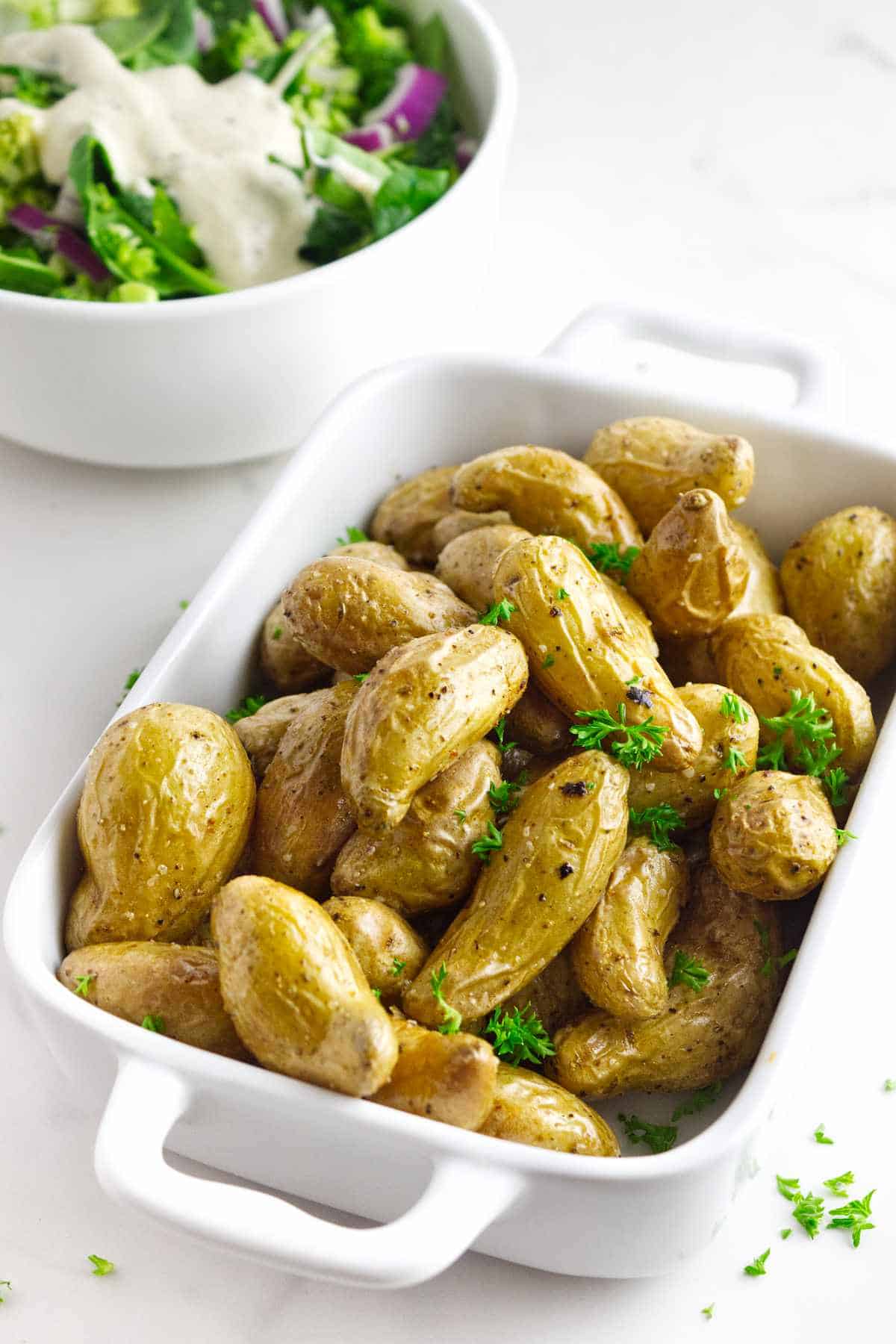 casserole serving dish filled with roasted fingerling potatoes garnished with parsley.