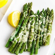 platter of roasted asparagus garnished with cheese and lemon.