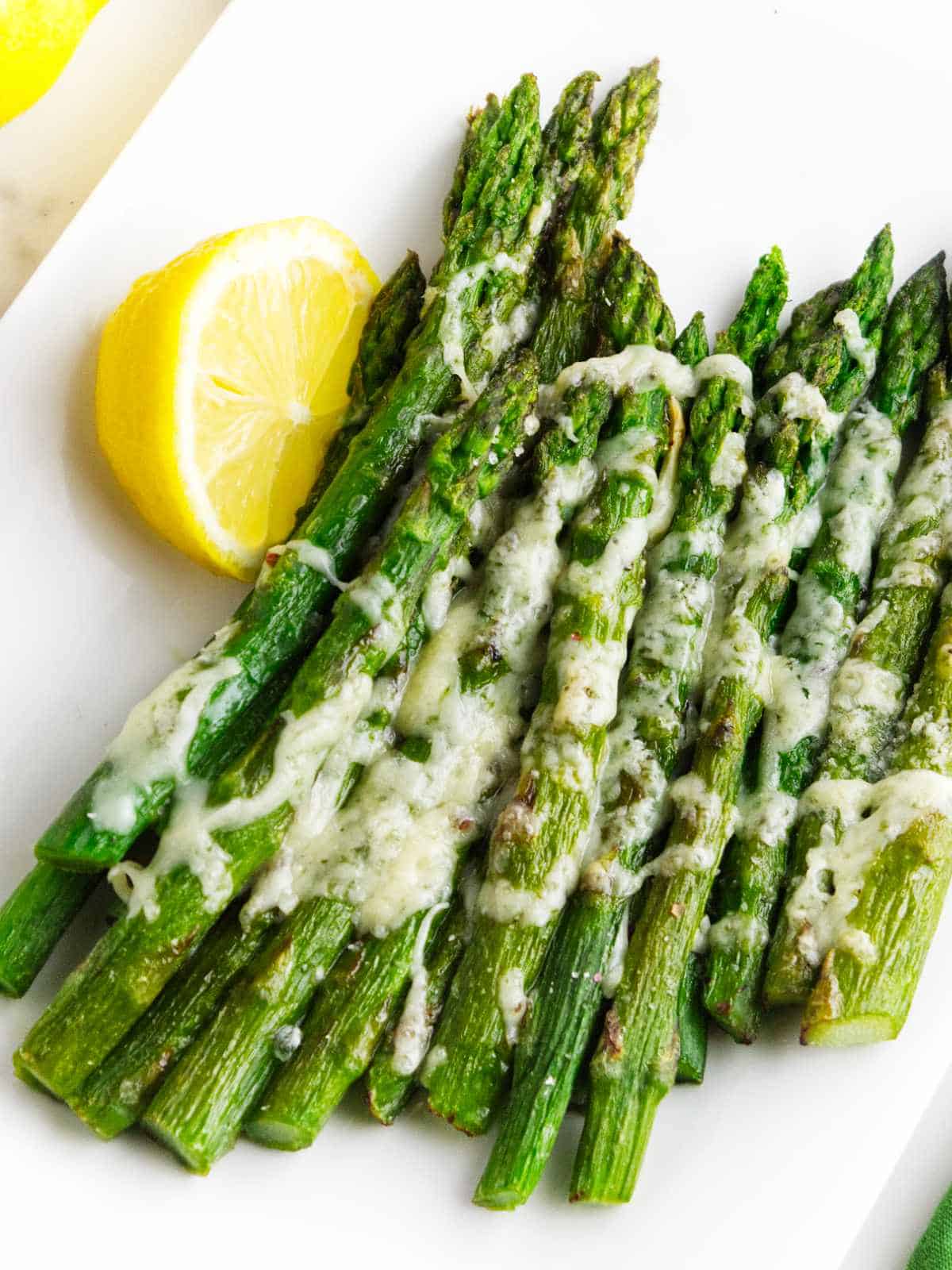 platter of roasted asparagus garnished with cheese and lemon.