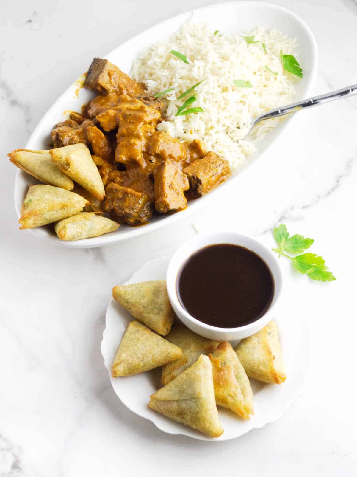 air fried samosa appetizers with dip and platter of rice and curry.