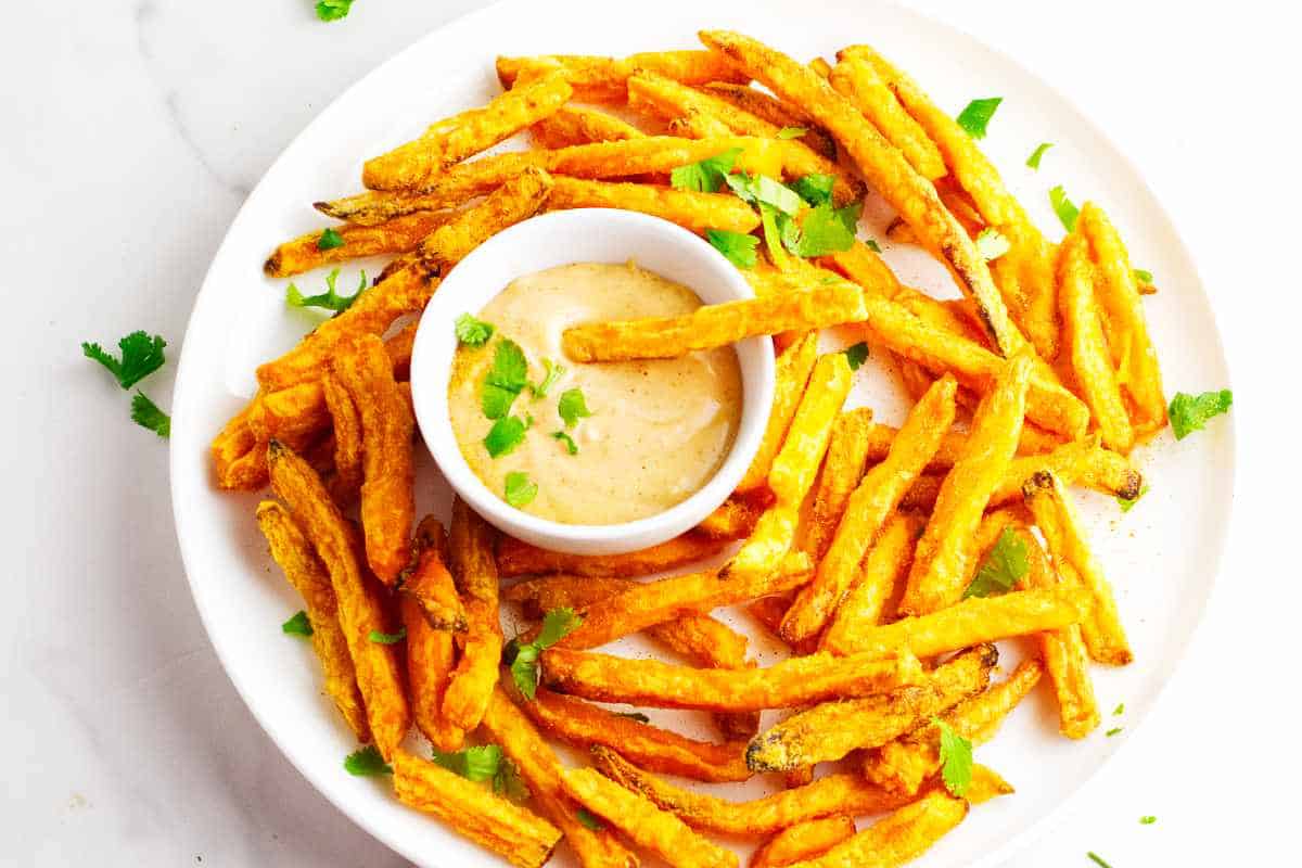 sweet potato fries on a platter with dipping sauce.
