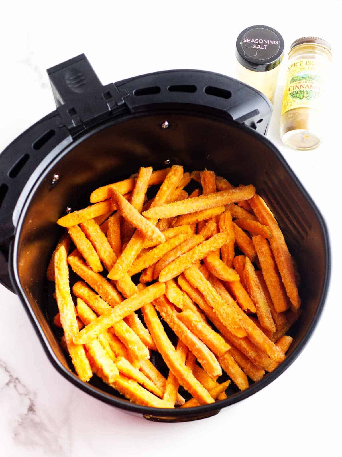frozen frites in an air fry basket with seasoning nearby.