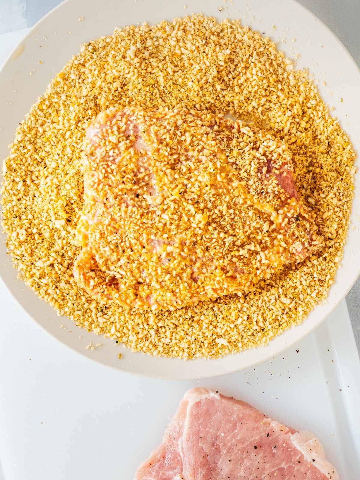 bowl of shake and bake coating for pork chops with coated chop inside.