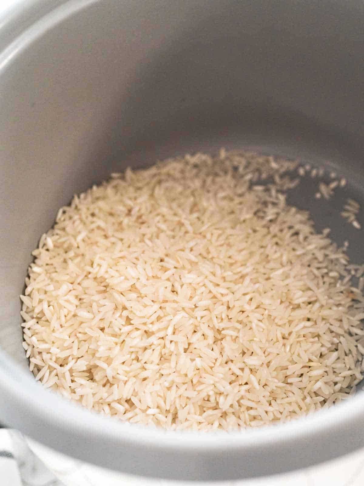 raw long grain rice in a rice cooker.