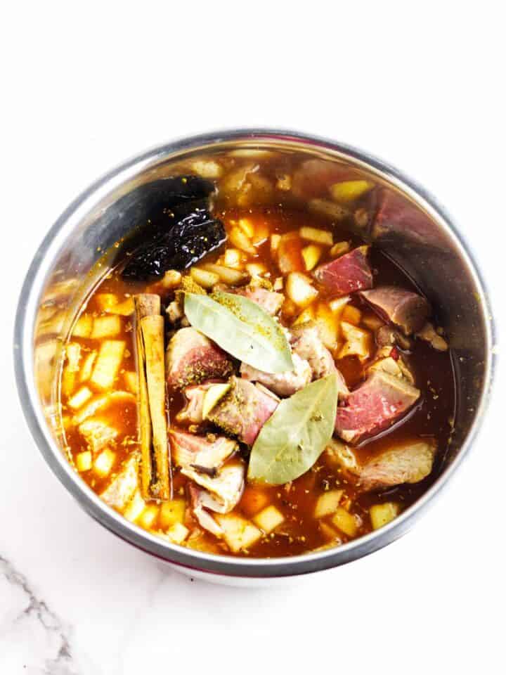 Instant Pot filled with beef, dried chiles, onion, garlic, cinnamon, and bay leaves for birria.