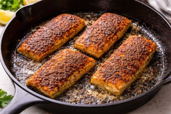 Two seasoned blackened mahi mahi fillets rest on a wire rack over a baking sheet, ready for cooking.