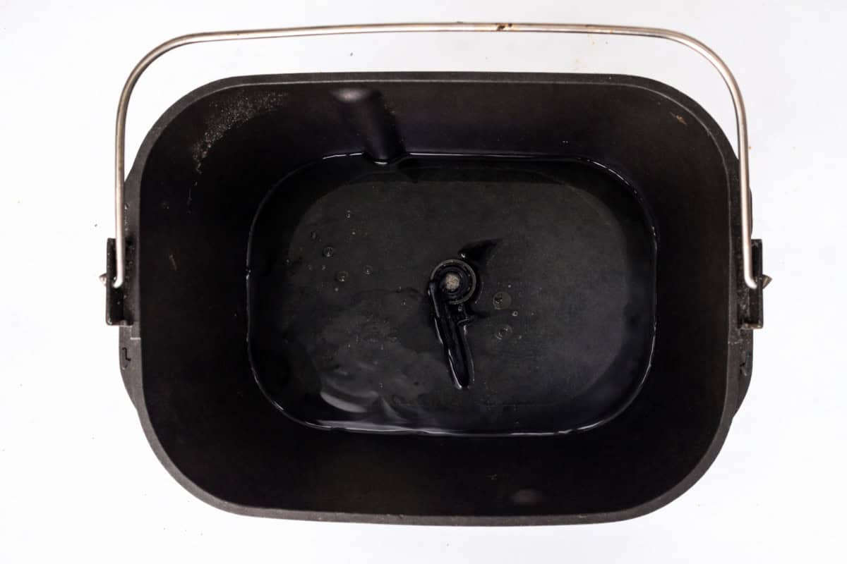 A top view of a bread machine pan containing water.