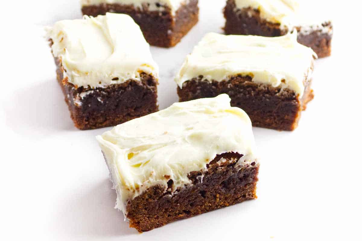 chocolate brownies with cream cheese frosting on a white background.