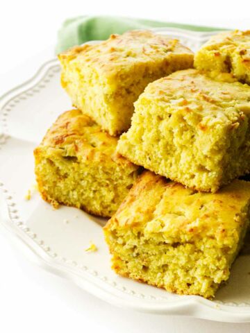 a white plate with stacked squares of Cajun Cornbread.