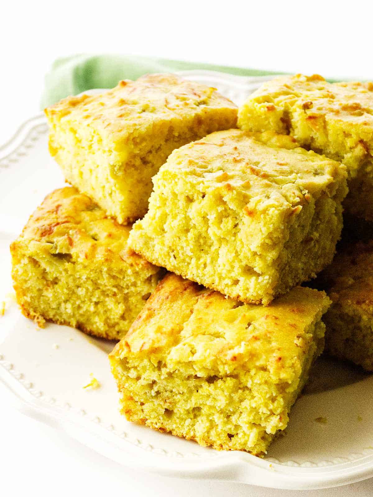 a white plate with stacked squares of Cajun Cornbread.