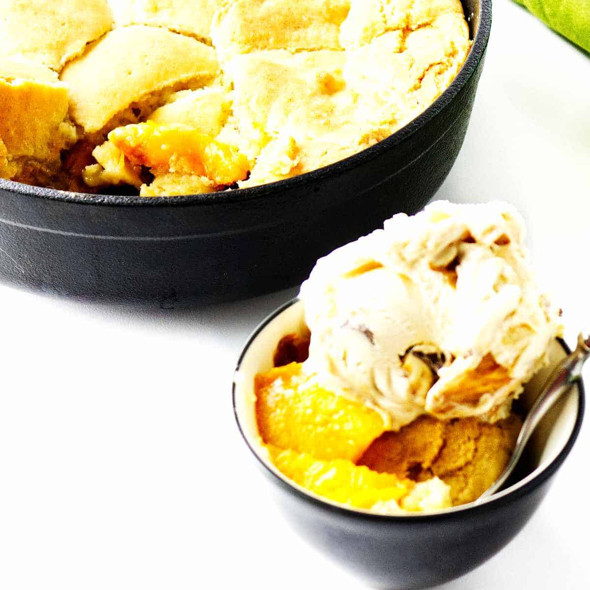 peach cobbler in a bowl with ice cream on top.