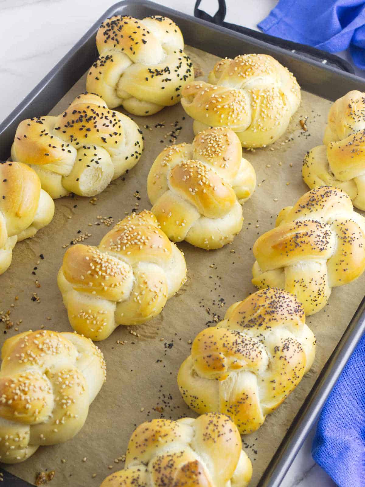 golden brown challah rolls fresh from the oven on a baking sheet.