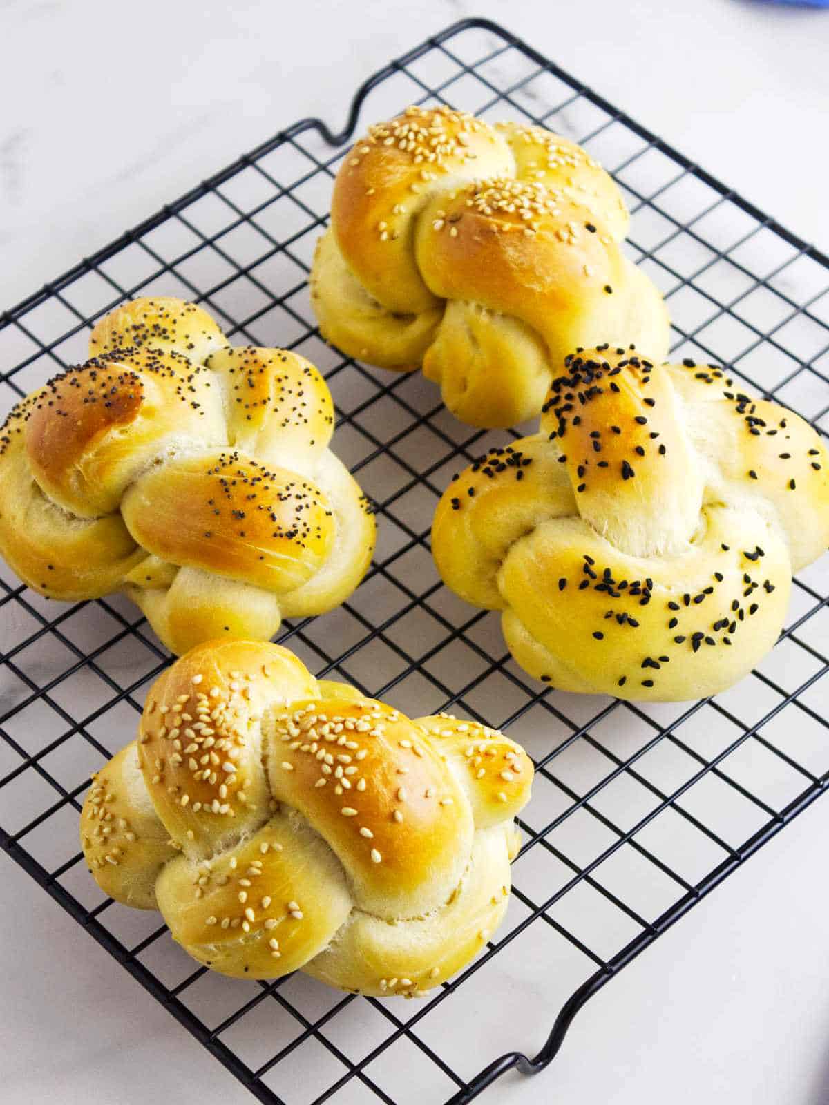 golden brown challah rolls fresh from the oven on a cooling rack.