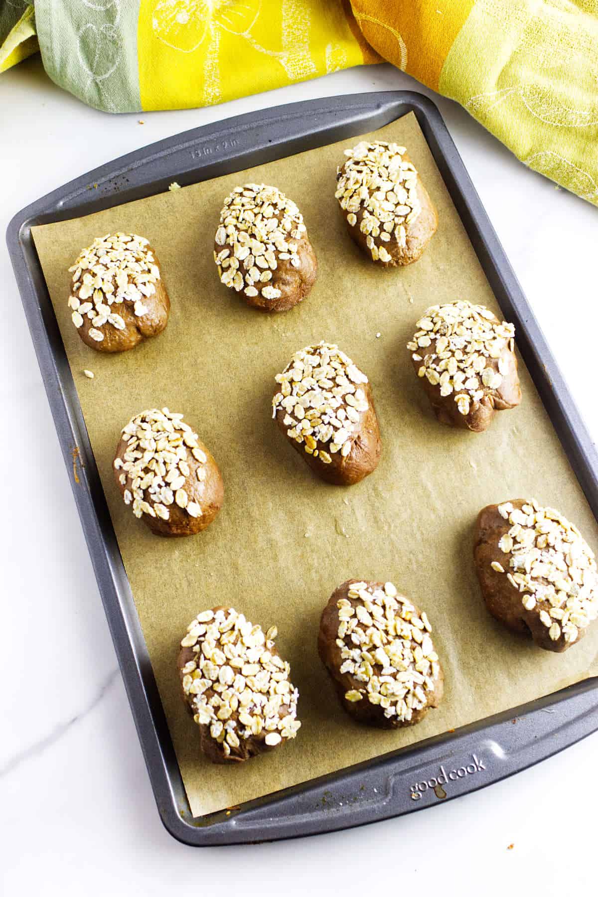 Brown bread rolls topped with oats before baking.