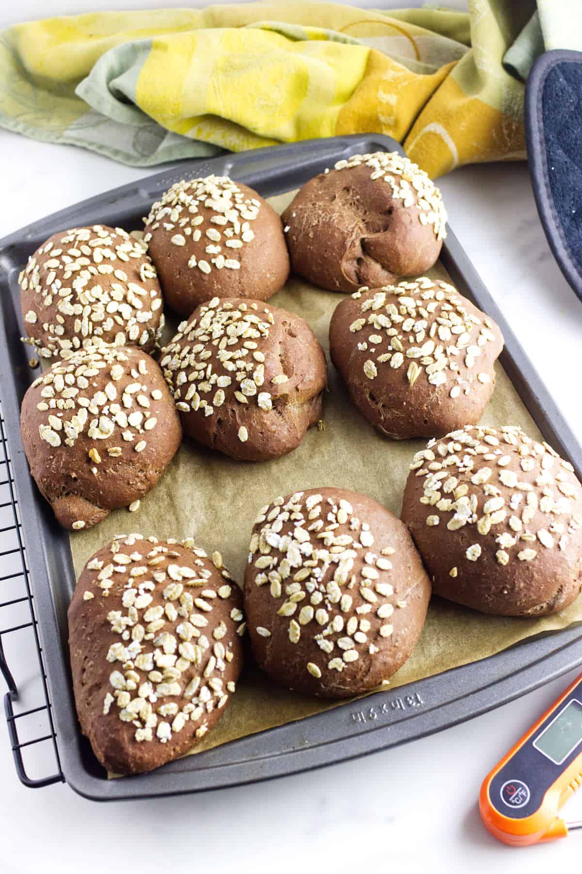 Freshly baked Cheesecake Factory brown bread rolls on a parchment lined baking sheet.