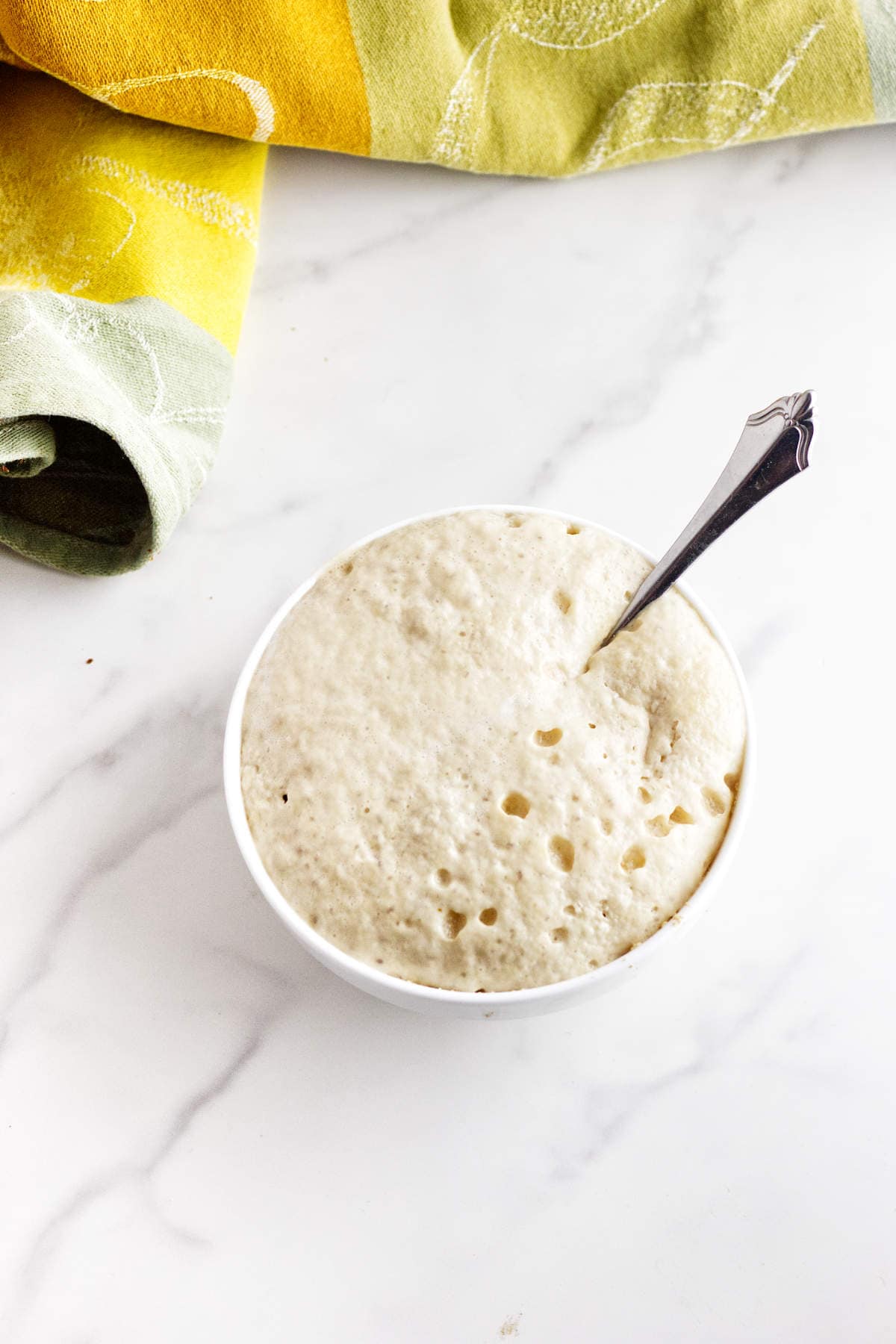 Foamy yeast mixture in a bowl for Cheesecake Factory brown bread rolls.