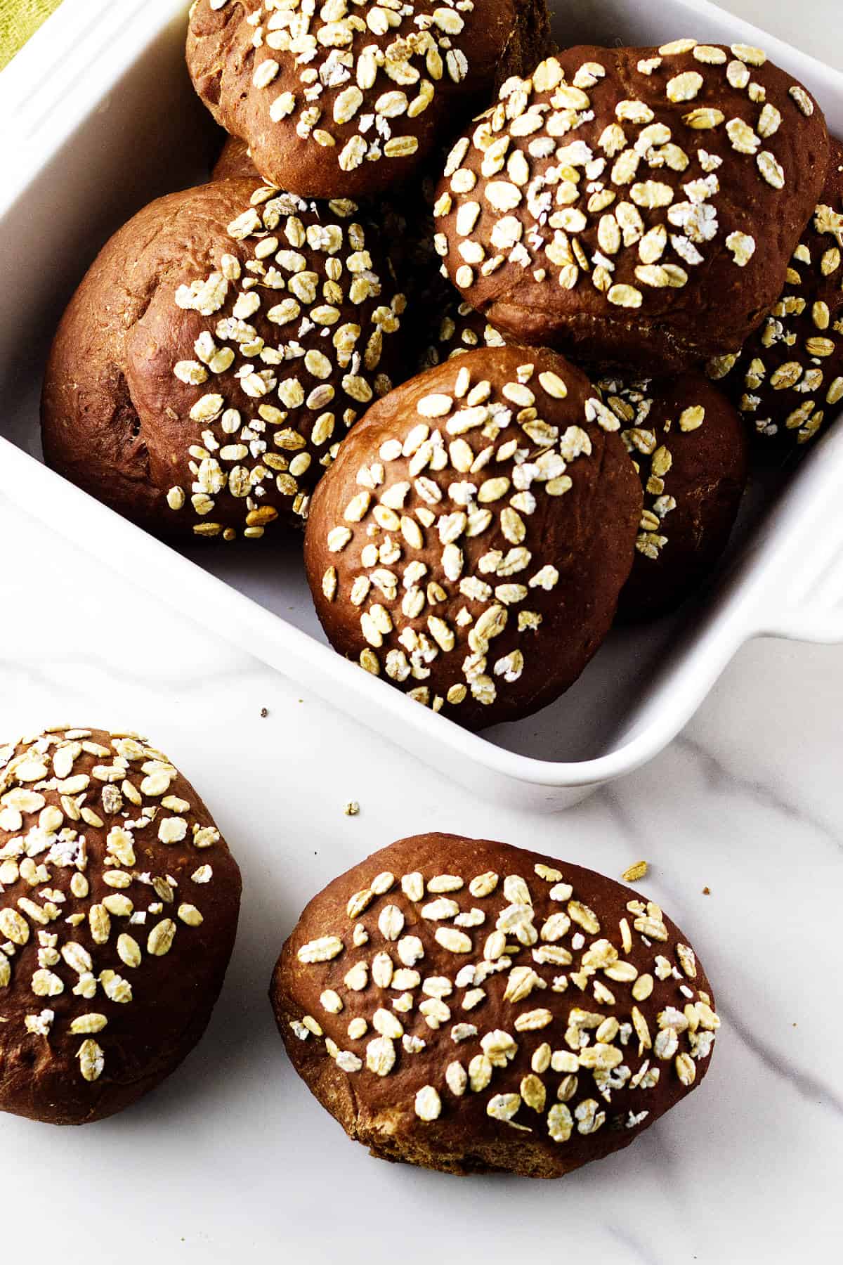 Cheesecake Factory Brown Bread Rolls topped with oats in a white baking dish.